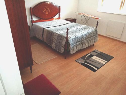 a bedroom with a bed and a wooden floor at Moradia Vila Rosa in Ponte de Vagos