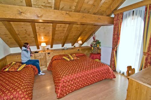 a person sitting on a phone in a room with two beds at Albergo Valbella in Gallio
