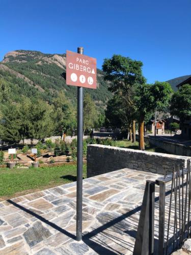 a sign on a pole in a park with a mountain at Apartaments Giberga in LʼAldosa