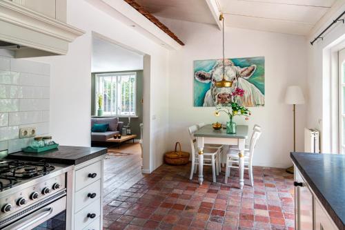 a kitchen with a table with a cow painting on the wall at Gastenverblijf KortVertoef in Kortenhoef