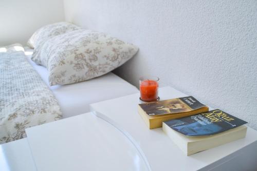 a bed with two books and a candle on a table at Apartman “Centar Jajce “ in Jajce