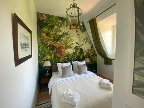 - une chambre avec un grand lit et du papier peint tropical dans l'établissement Magnifique deux pièces au calme, à Deauville