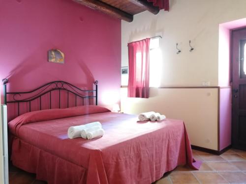 a pink bedroom with a bed with towels on it at Borgo i Stritti in Petralia Soprana