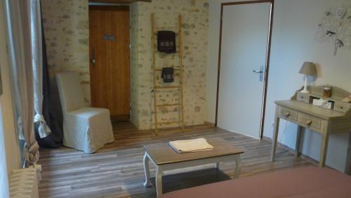 ein Wohnzimmer mit einem Tisch, einem Schreibtisch und einem sidx sidx in der Unterkunft A L'OMBRE DU TEIL in Bouville