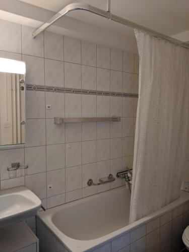 La salle de bains blanche est pourvue d'une baignoire et d'un rideau de douche. dans l'établissement Schiablick - Broggini, à Davos