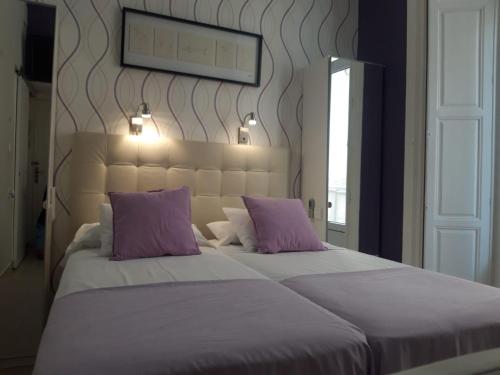 a bedroom with a large bed with purple pillows at Apartamentos Marques De La Merced in Málaga