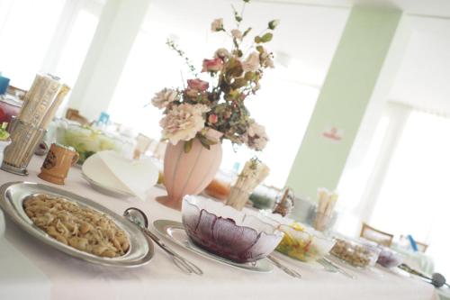 einen Tisch mit einem Teller Essen und eine Vase mit Blumen in der Unterkunft Hotel Internazionale in San Mauro a Mare