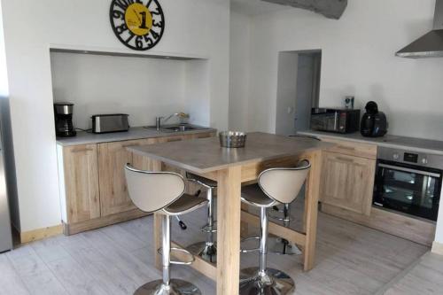 eine Küche mit einem Holztisch und 2 Hockern in der Unterkunft charmante maison normande luneray in Luneray