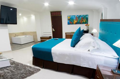 a bedroom with a large bed with blue pillows at Hotel Caquetá Real HSC in Florencia