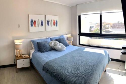 sypialnia z niebieskim łóżkiem i oknem w obiekcie Ideal departamento en el corazón de Los Dominicos w mieście Santiago
