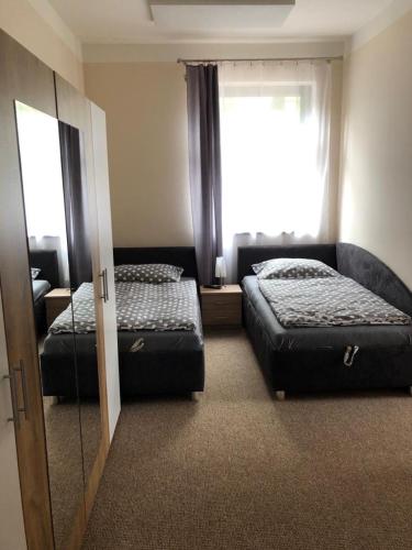 a bedroom with two beds and a mirror and a window at Penzion Florian in Moldava