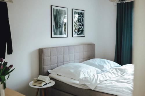 a bed with white sheets and two pictures on the wall at Seeblick & Terrasse! Moderne Ferienwohnung 96qm in Großräschen