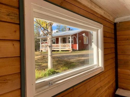 - une fenêtre dans une maison avec vue sur une grange dans l'établissement Wilderness in off-grid cabin in Lapland, à Nattavaara