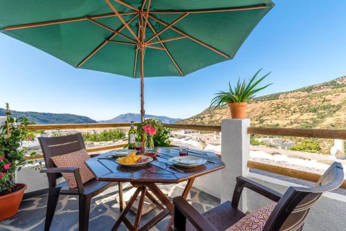 a table and chairs with an umbrella on a patio at Apartamentos Entre Senderos in Capileira