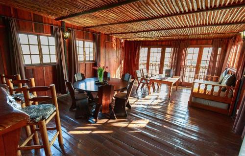 a dining room with a table and chairs and windows at Rain Farm Game Lodge in uMhlali
