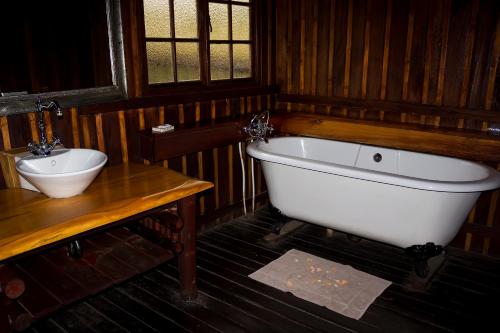 a bathroom with a white bath tub and a sink at Rain Farm Game Lodge in uMhlali