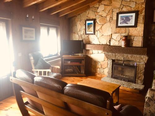 a living room with a couch and a stone fireplace at Artesano II in Navarredonda de Gredos