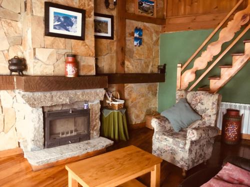 a living room with a stone fireplace and a chair at Artesano II in Navarredonda de Gredos
