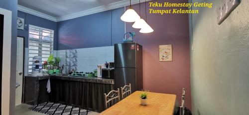 a kitchen with a wooden table and a refrigerator at Teku Homestay Geting Tumpat Kelantan in Kampong Geting