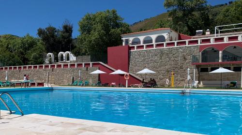 une grande piscine en face d'un bâtiment dans l'établissement Casas de Alpedrinha, à Alpedrinha