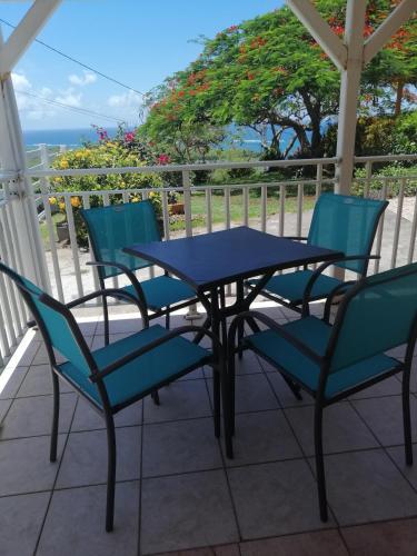a table and chairs on a patio with a view of the ocean at Villa le flamboyant in Le Marin