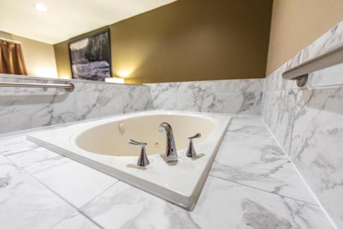 a bathroom with a white tub and a sink at Super 8 by Wyndham Kamloops On The Hill in Kamloops