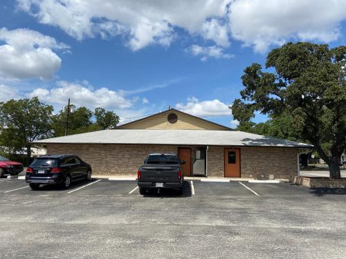 a building with two cars parked in a parking lot at Redbud Inn in Goldthwaite