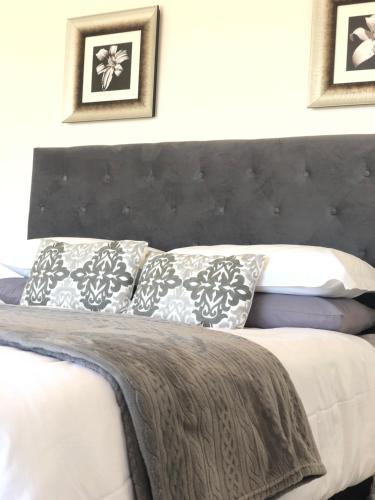 um quarto com uma cama com uma cabeceira e almofadas pretas em Views at 69 B&B em Langebaan