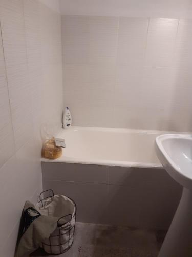 ein Bad mit einer Badewanne, einem Waschbecken und einem Korb in der Unterkunft Apartament particular in Râmnicu Vâlcea