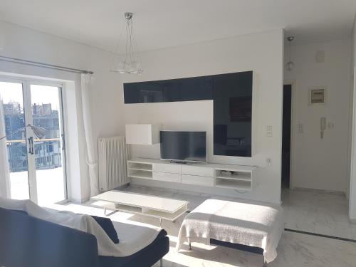 een witte woonkamer met een tv en een bank bij NN Larisa Deluxe Apartment in Larisa