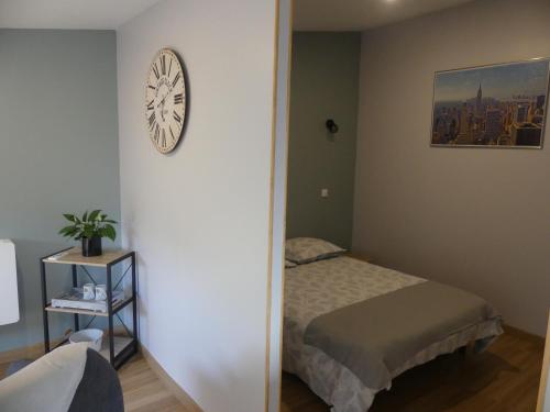 a bedroom with a bed and a clock on the wall at charmant studio 35m² au calme proche du circuit in Saint-Gervais en-Belin