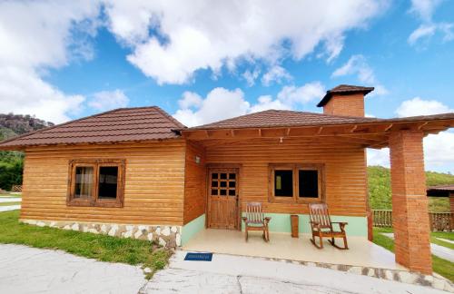 a wooden house with two chairs and a porch at Villas Las Neblinas in Constanza