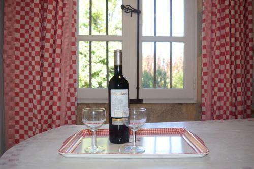 a bottle of wine and two wine glasses on a tray at l'Empereur - La Maïsou in Sérignac