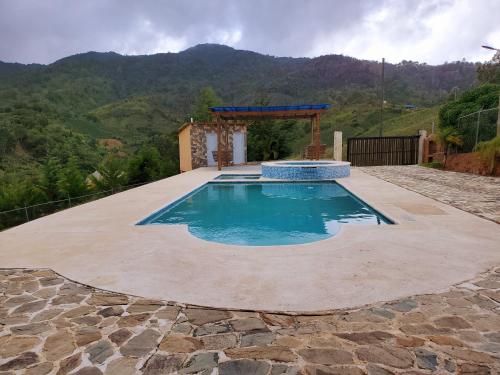 een zwembad in een tuin met een berg op de achtergrond bij Villas Las Neblinas in Constanza