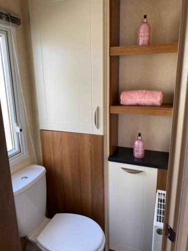 a small bathroom with a toilet and pink towels at Vista Caravan Hire in Seasalter