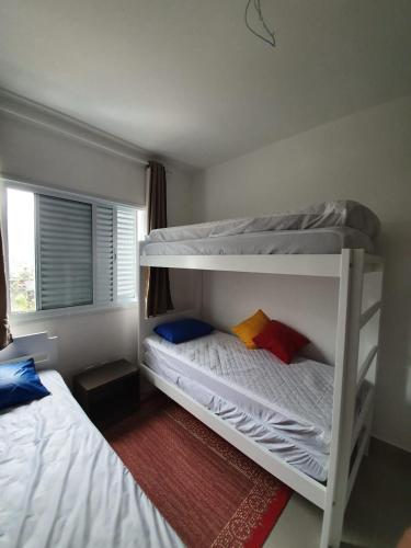 a bedroom with two bunk beds and a window at Apto Praia das Toninhas in Ubatuba