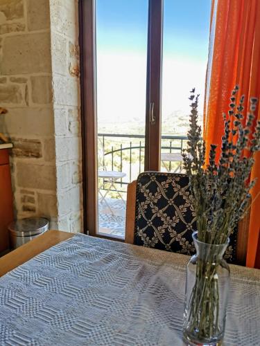 a vase of flowers sitting on a table with a window at Aelia in Kamilari