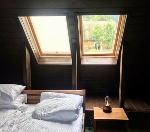 a bedroom with two windows and a bed and a table at Садиба Остра in Sherbovtsy