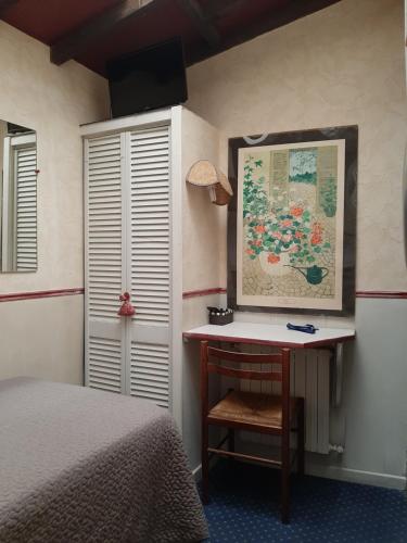 a bedroom with a desk with a bed and a painting at Hotel Mignon in Avignon
