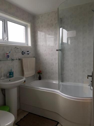 a white bathroom with a tub and a sink at Quiet, spacious double bedroom! in Peterborough