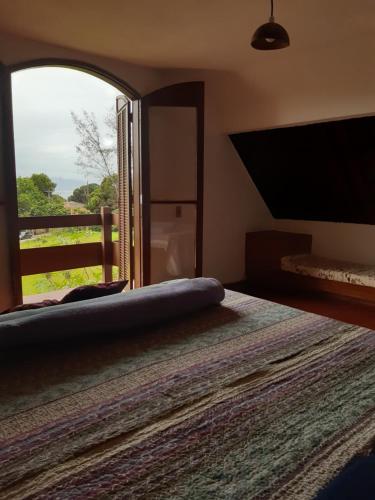 1 dormitorio con 1 cama y ventana grande en Chalé à 300 m da praia Rasa, com horta orgânica, en Búzios