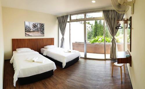 um quarto de hotel com duas camas e uma grande janela em The Pines at Fraser's Hill, Malaysia em Bukit Fraser
