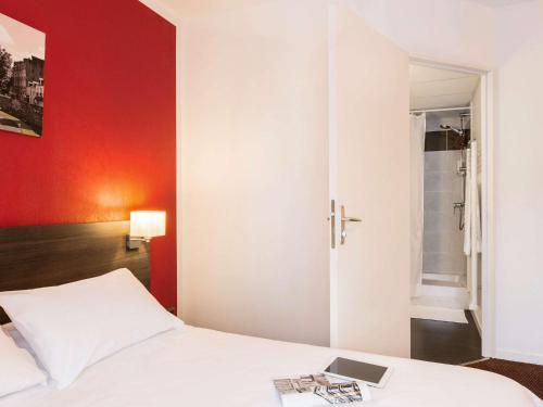 une chambre avec un lit blanc et un mur rouge dans l'établissement Aparthotel Adagio Access Nantes Viarme, à Nantes