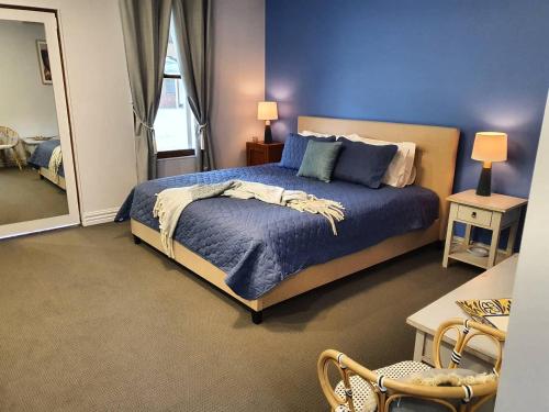 a bedroom with a large bed with a blue wall at The Lancefield Lodge in Lance Field