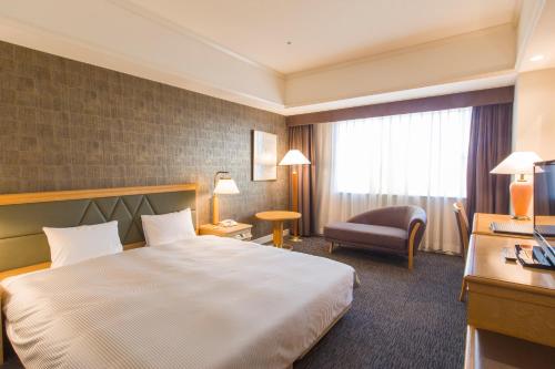 千葉市にあるThe QUBE Hotel Chibaの大きなベッドと椅子が備わるホテルルームです。