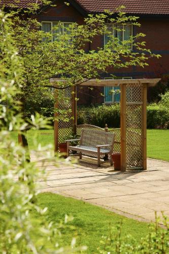 a bench in a garden with a gazebo at Mercure Daventry Court Hotel in Daventry