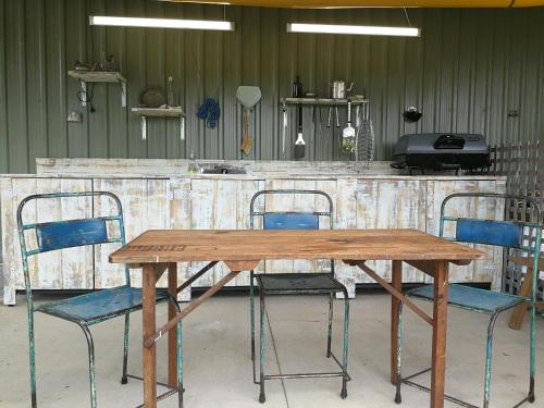 einen Holztisch mit zwei Stühlen und einer Theke in der Unterkunft Kakariki Rooms, Kotare House in Tawharanui