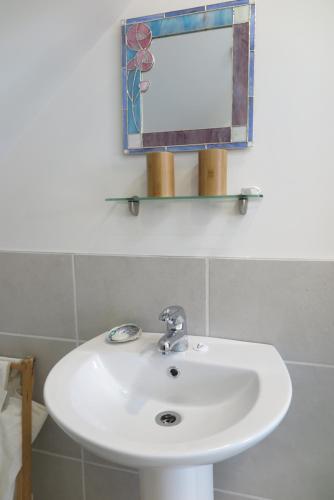 lavabo blanco en el baño con espejo en Ruru Lodge en Tawharanui