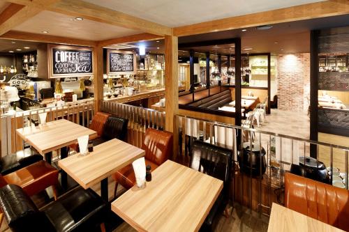 札幌市にあるKOKO HOTEL 札幌駅前の木製のテーブルと椅子のあるレストラン、バー