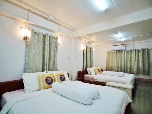 2 camas en una habitación con cortinas verdes en Doi Samoe Dao Hostel, en Nan